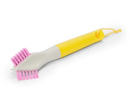 Une brosse avec un manche jaune et des poils roses est posée en diagonale sur un fond blanc.
