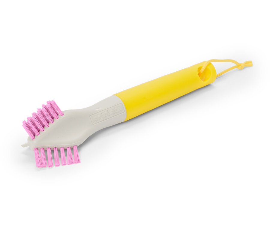 Une brosse avec un manche jaune et des poils roses est posée en diagonale sur un fond blanc.