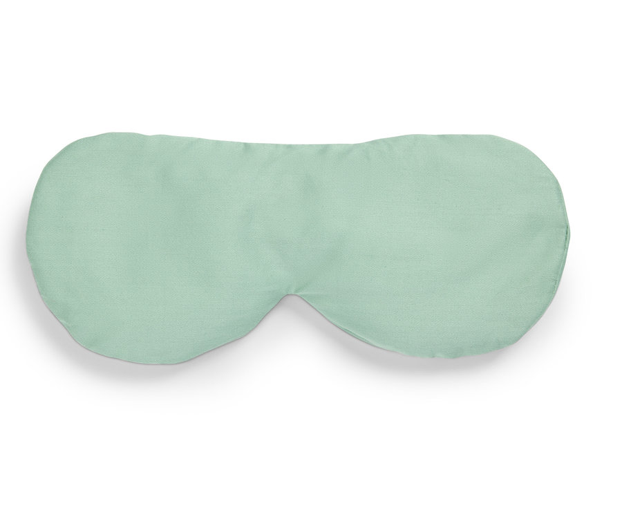 Un masque de sommeil vert clair repose sur un fond blanc.