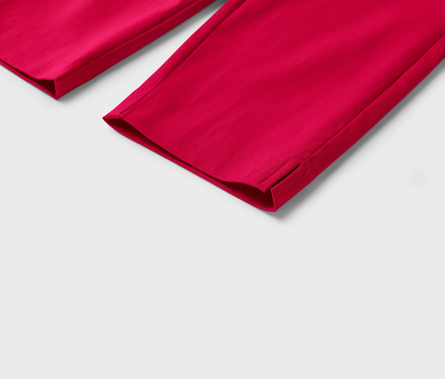 Gros plan sur le bas de pantalon rouge avec de petites fentes sur l'ourlet sur fond blanc.