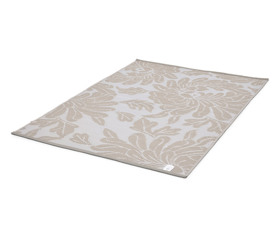 Un tapis beige à motif floral est posé sur un fond blanc.