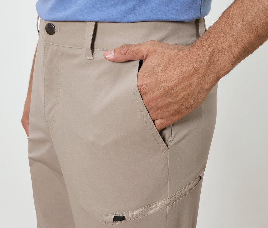 Homme avec la main dans la poche d'un pantalon beige.