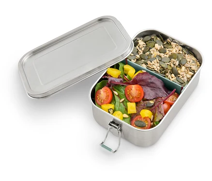 Boîte à lunch en métal ouverte avec salade et graines.