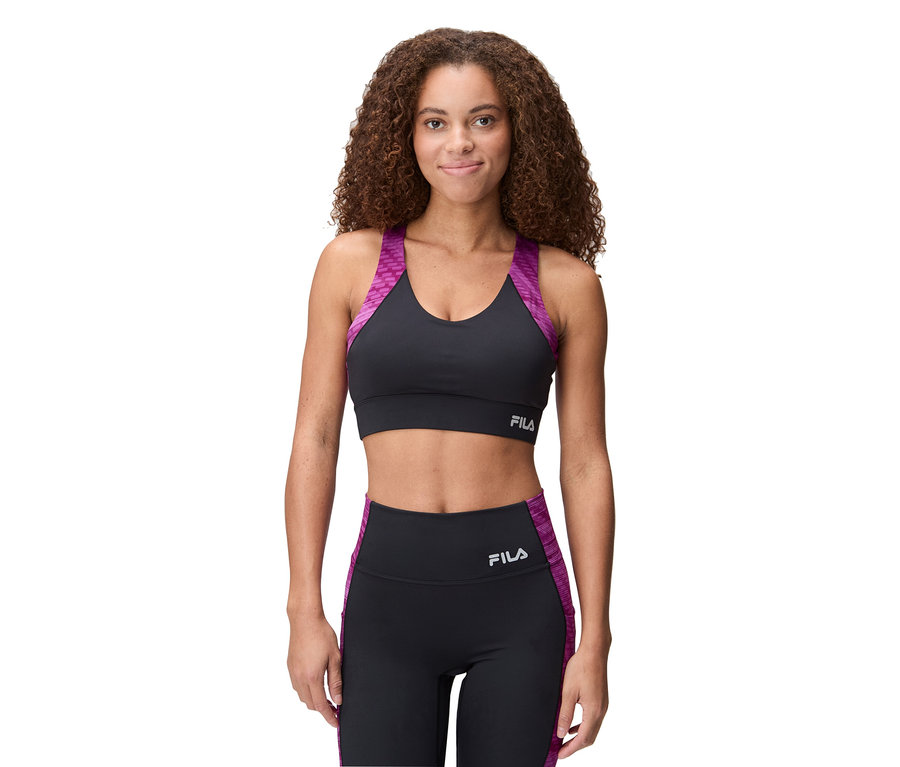 Femme portant un soutien-gorge de sport Fila noir avec des détails violets et un legging assorti.