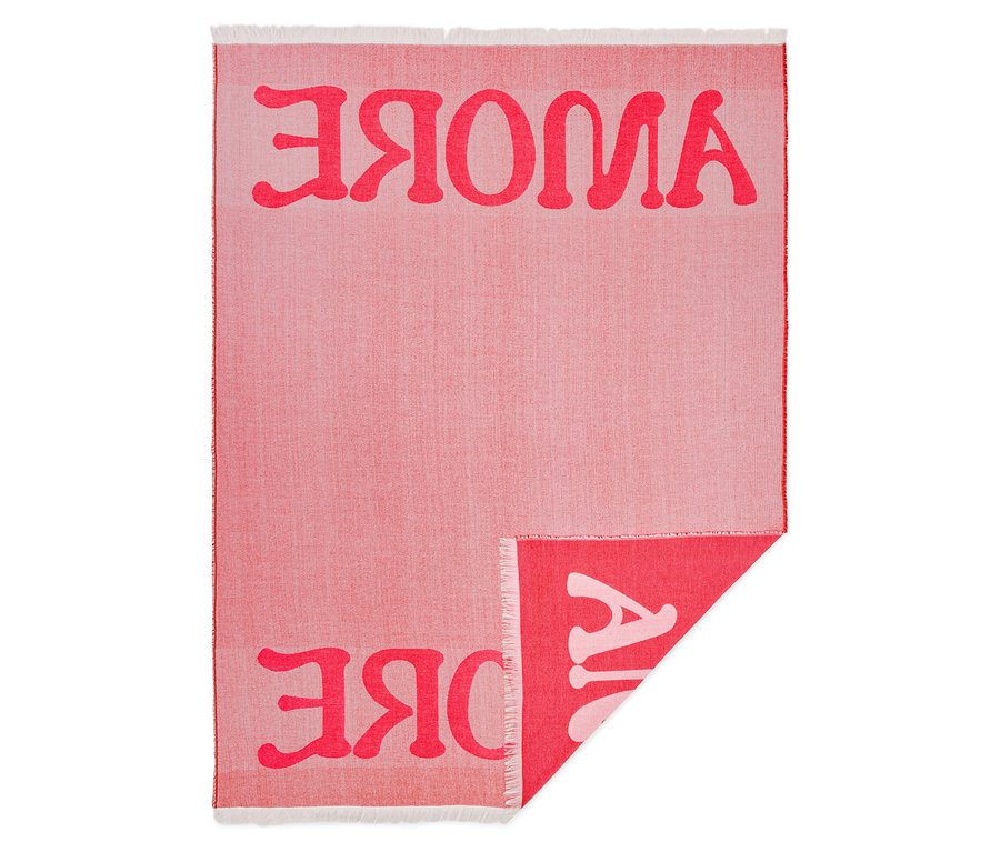 Gros plan d'une couverture rouge clair avec l'inscription "AJVOKE" en rouge plus foncé, une partie de la couverture étant repliée.