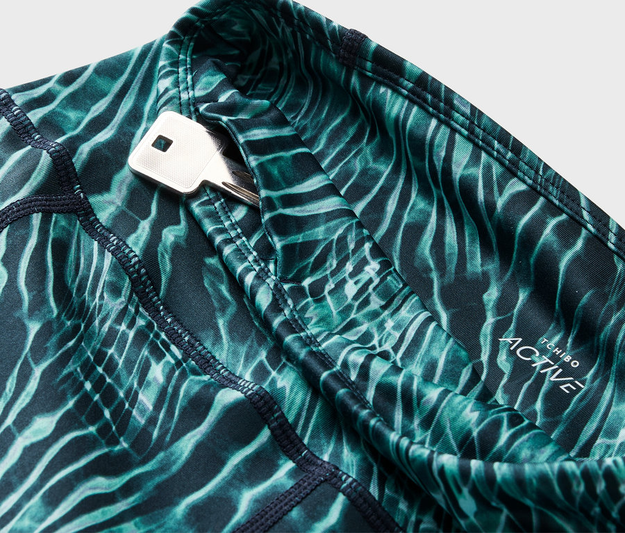 Gros plan sur un legging à motifs bleu-vert avec une poche à clés dans laquelle se trouve une clé.