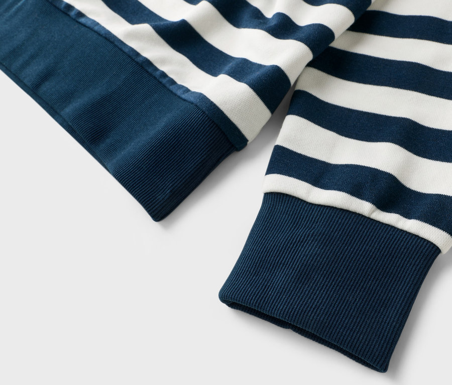 Gros plan sur les manches d'un pull rayé bleu et blanc.