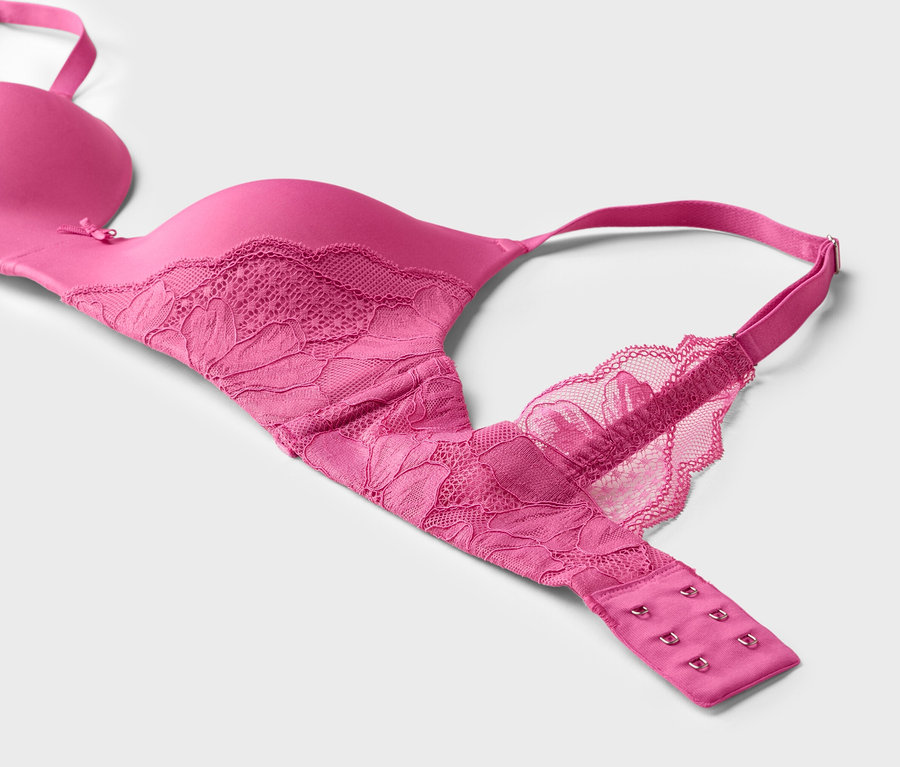 Gros plan d'un soutien-gorge rose avec de la dentelle sur fond blanc.