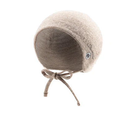 Un bonnet de bébé beige avec des protège-oreilles et des liens à nouer, orné d'un petit logo sur le côté.