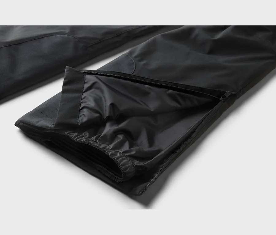 Pantalon noir avec une fermeture éclair ouverte sur la jambe, révélant une doublure intérieure froncée et un ourlet élastique.