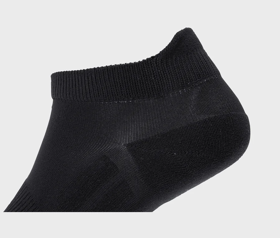 Gros plan d'une chaussette noire basse avec un bord-côte et des sections de tissu plus fin et transparent.