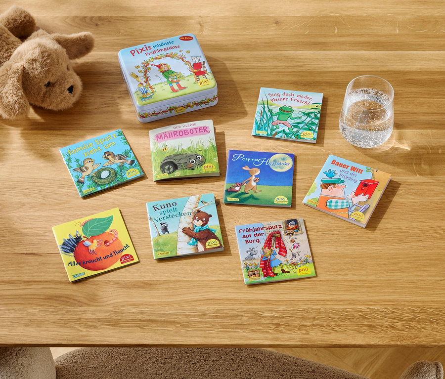 Sur une table en bois sont posés une peluche, une boîte et plusieurs livres Pixi à côté d'un verre d'eau.