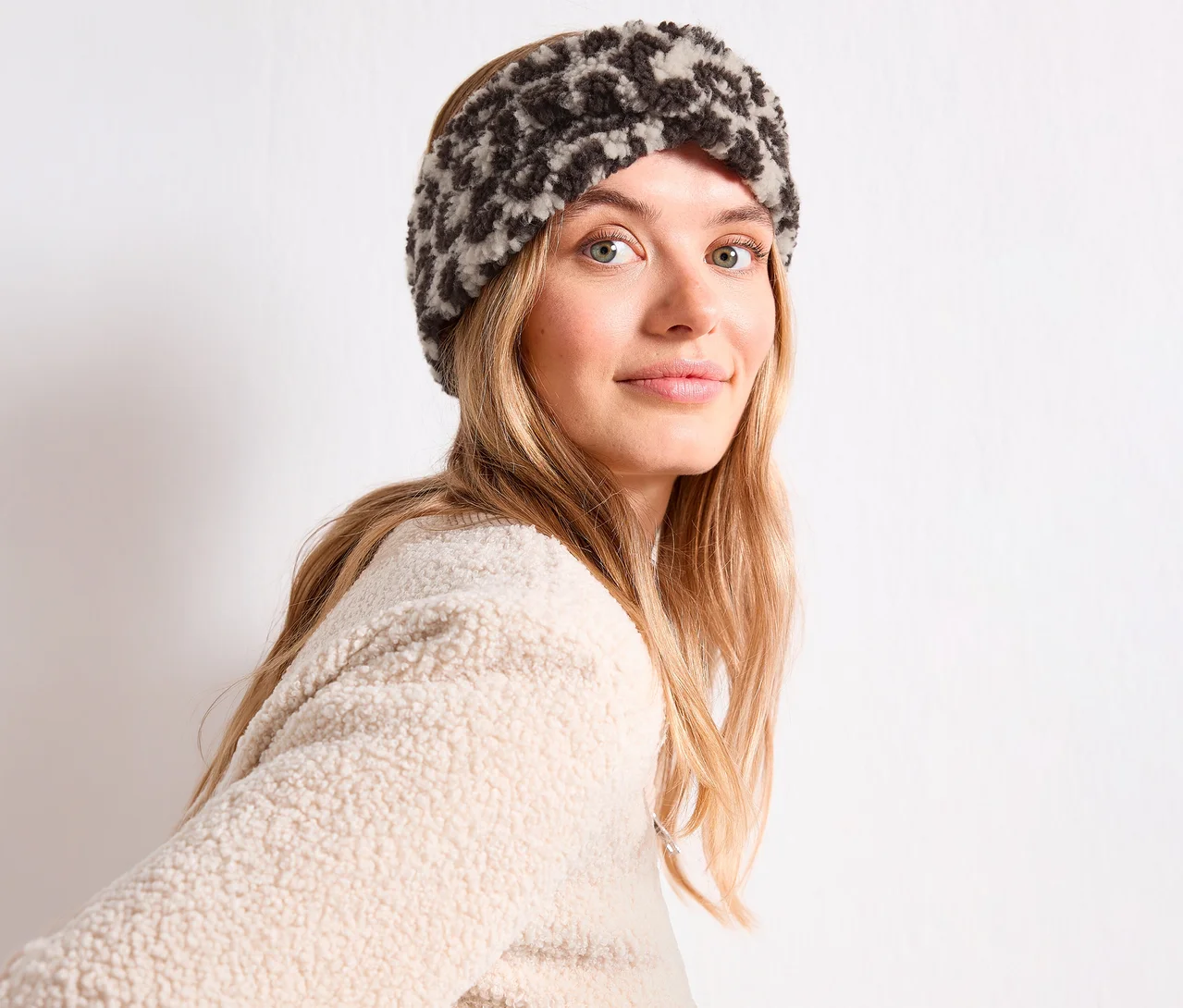 Femme aux cheveux blonds longs portant un bandeau Street One à imprimé léopard gris foncé et crème et un pull en polaire crème.