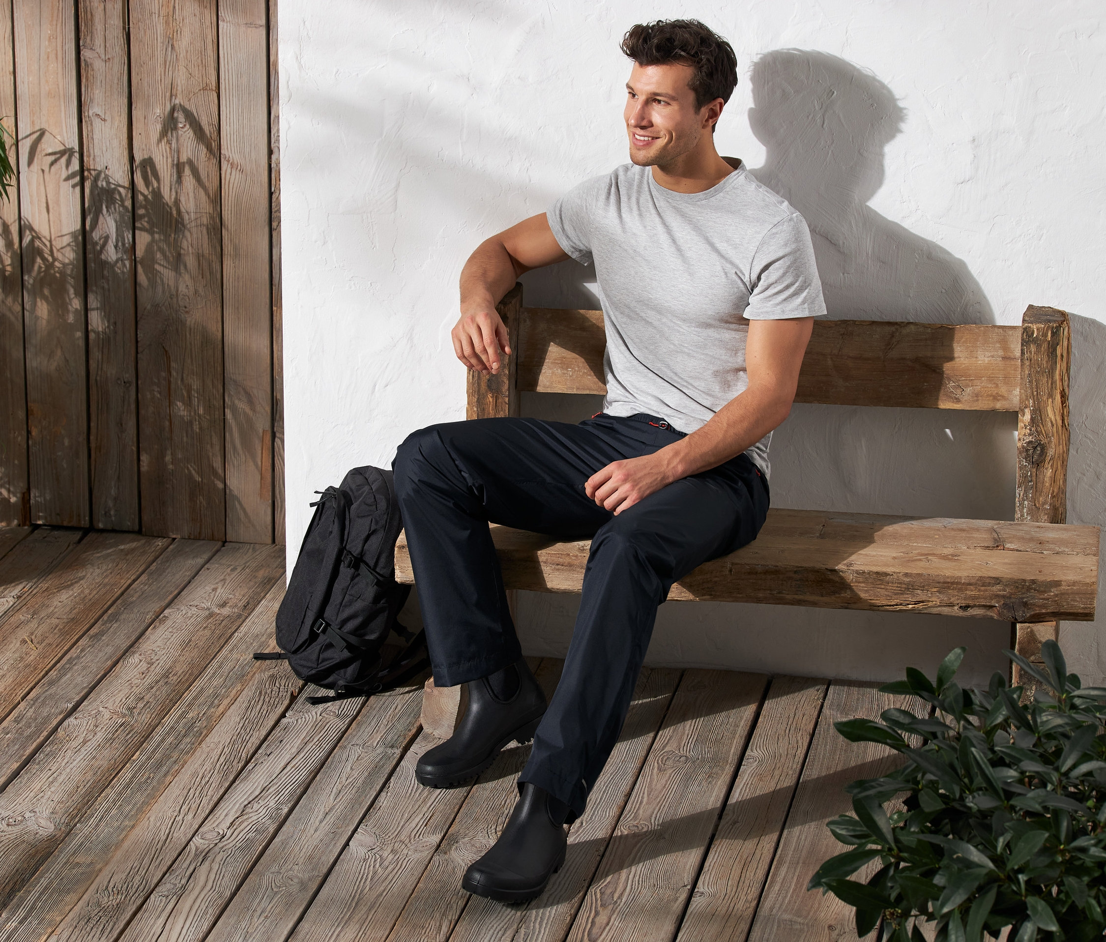 Un homme est assis sur un banc et porte un pantalon de pluie unisexe.