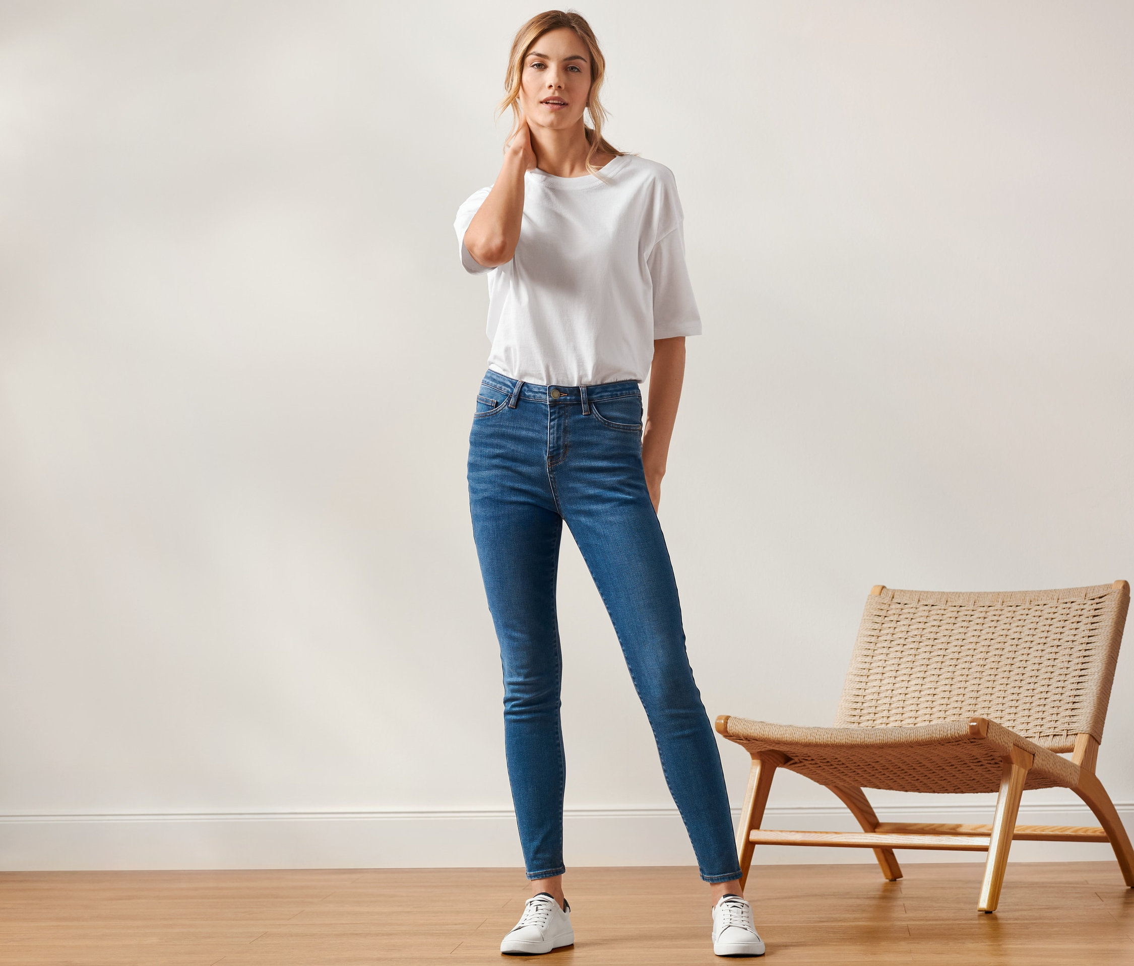 Femme posant en jean skinny « Fit Hanna », t-shirt blanc et baskets.