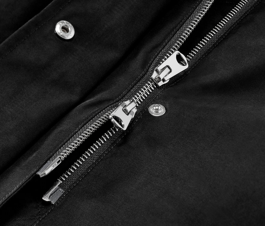 Gros plan sur une parka à capuche noire avec une fermeture éclair argentée.