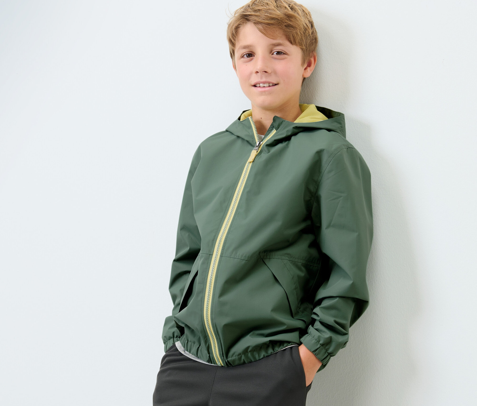 Un garçon pose, portant une veste fonctionnelle de sport pour enfant.