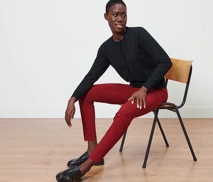Femme assise sur une chaise portant un pantalon stretch rouge.