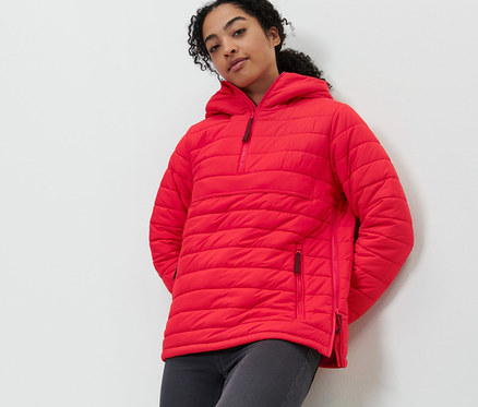 Femme posant en veste matelassée à capuche rouge.