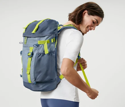 Femme ajustant les bretelles d'un sac à dos d’extérieur.