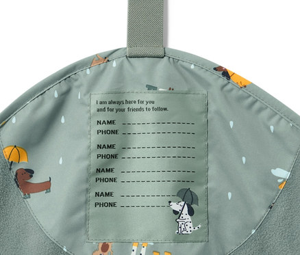 Détail d'un pantalon de pluie thermique pour enfant avec un imprimé de chien et une étiquette pour le nom.