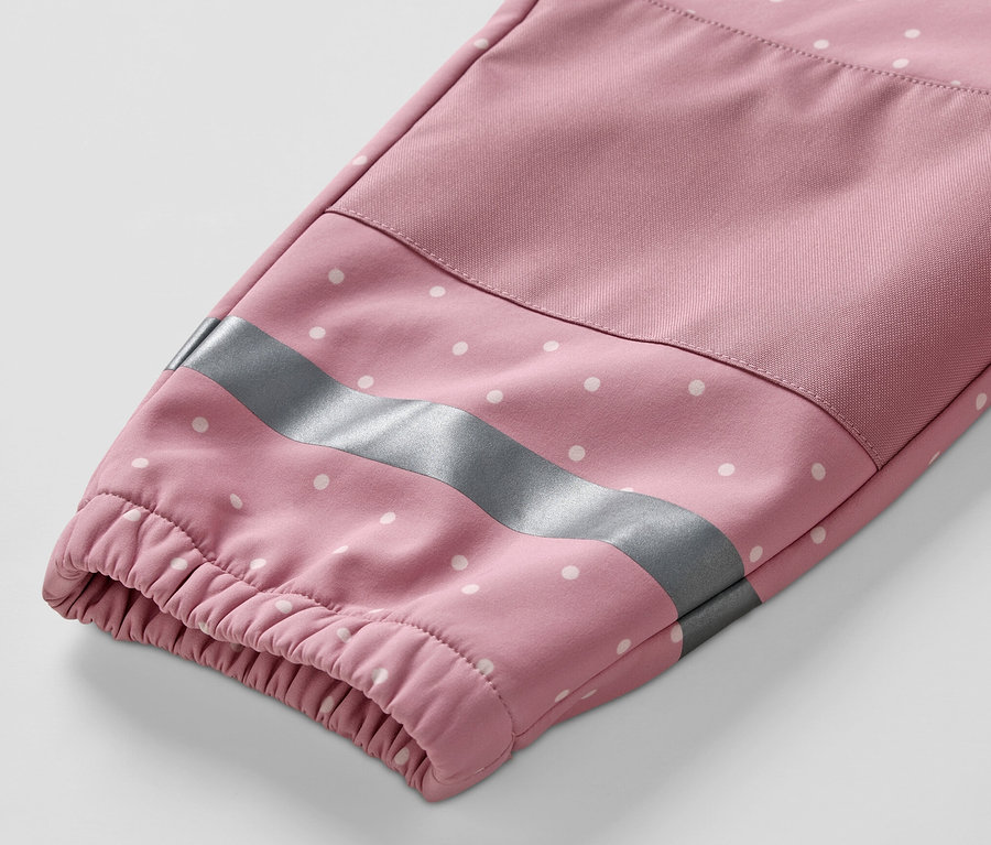 Gros plan sur la manche d'une combinaison en softshell pour enfant, à pois blancs avec une bande réfléchissante.
