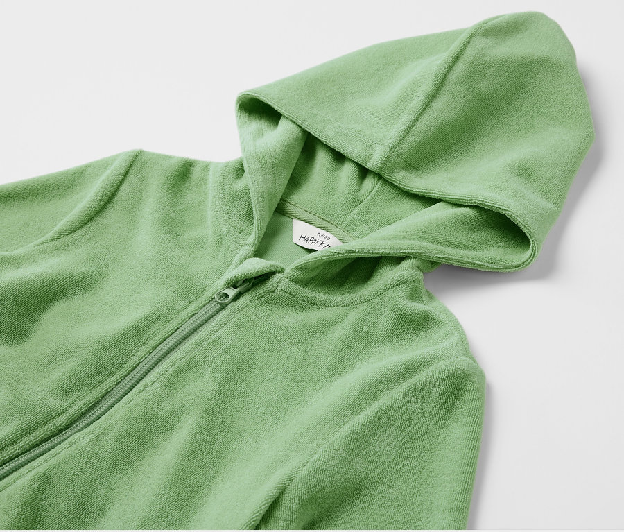 Gros plan sur une veste éponge pour enfants vert clair avec capuche et fermeture éclair.