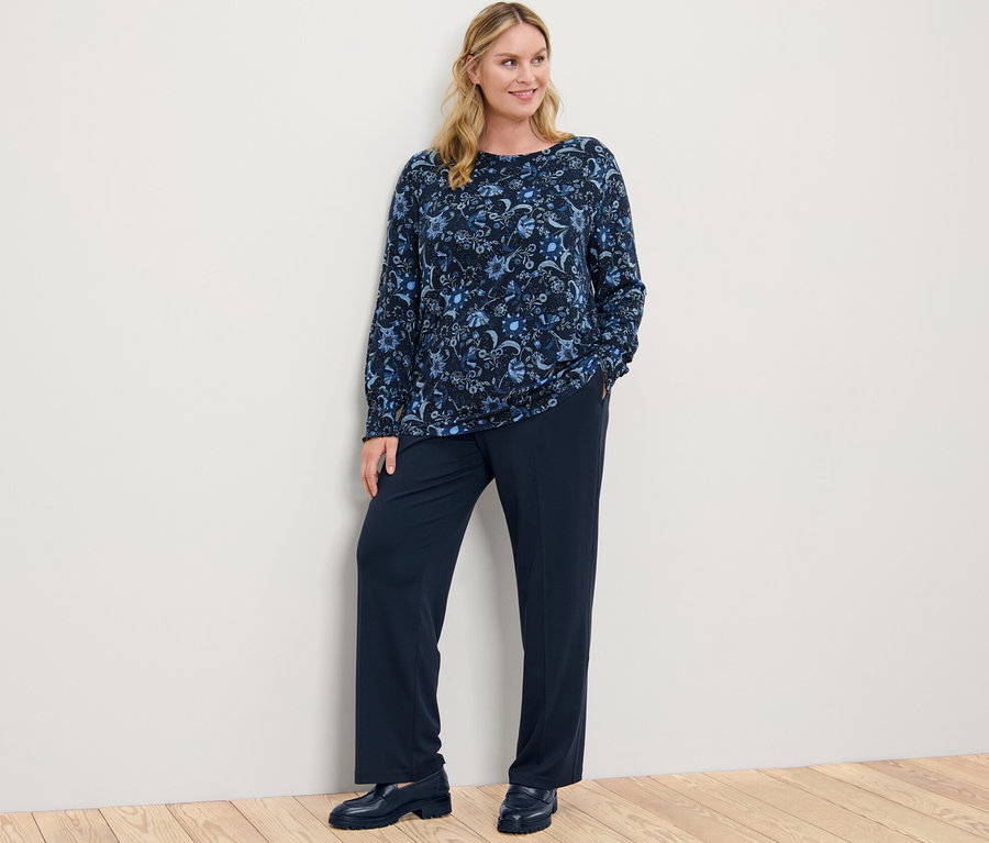 Femme posant portant un blouse imprimée et un pantalon en jersey confort.