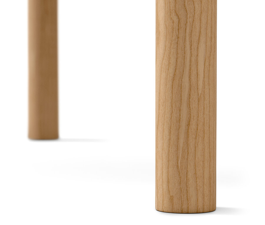 Gros plan sur deux pieds en bois clair d'une table basse sur fond blanc.