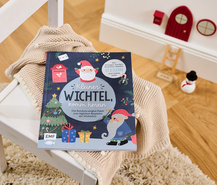 Le livre	: «	Kleiner Wichtel, komm herein	» (Entre, petit lutin, en allemand) est posé sur un pull sur une chaise blanche.
