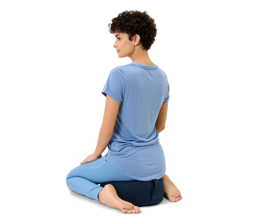 Femme assise sur un coussin de méditation.