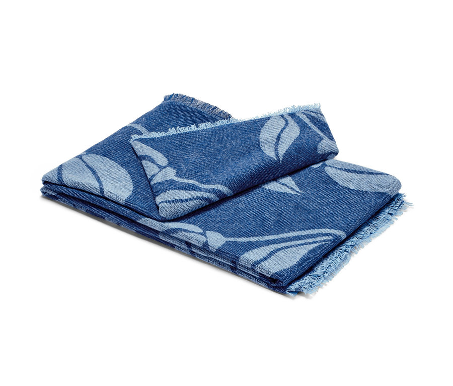 Couverture d’intérieur pliée avec franges et motif floral bleu.