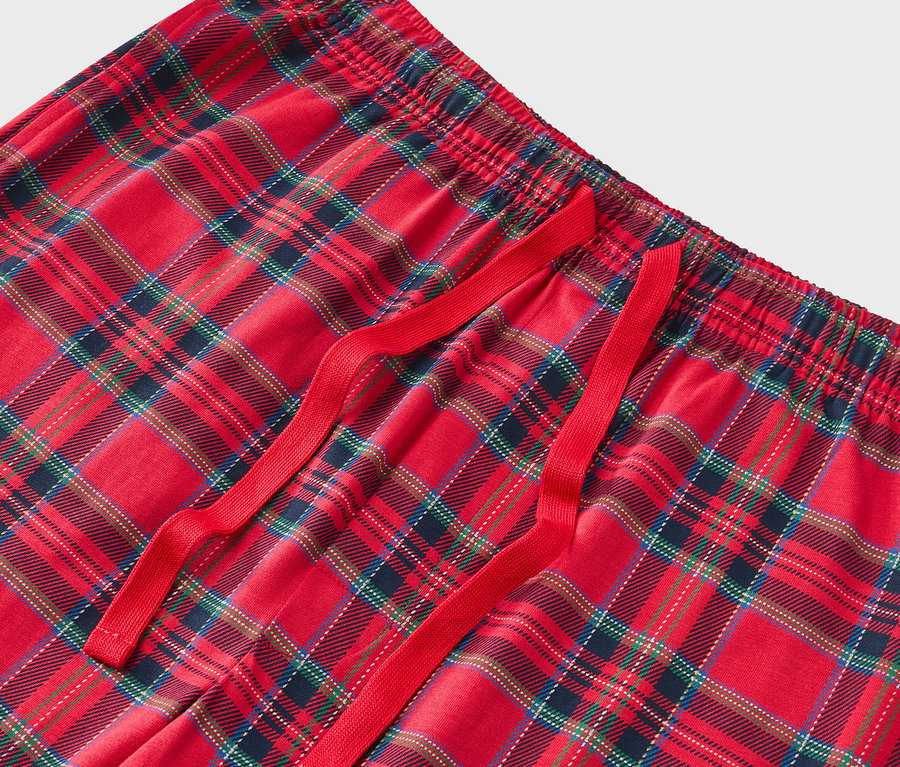 Détail d'un pantalon de pyjama à carreaux rouges avec un cordon de serrage rouge.