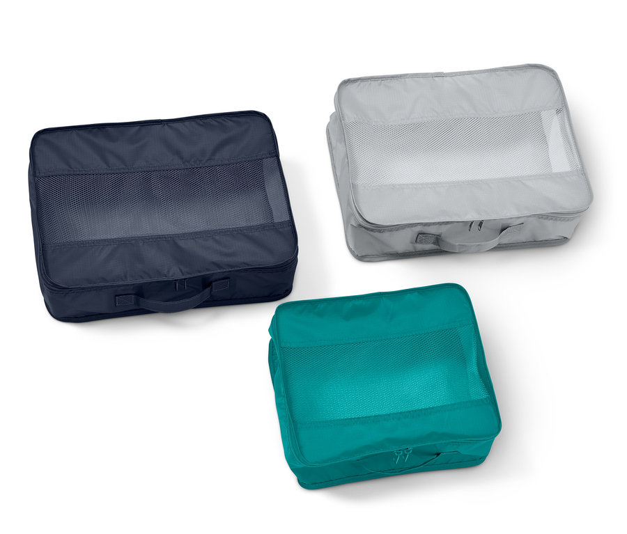 Trois sacs de rangement de voyage : bleu marine, gris et turquoise.