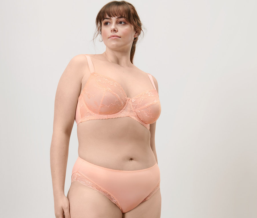 Femme posant en soutien-gorge à armatures en dentelle abricot et slip mi-haut.