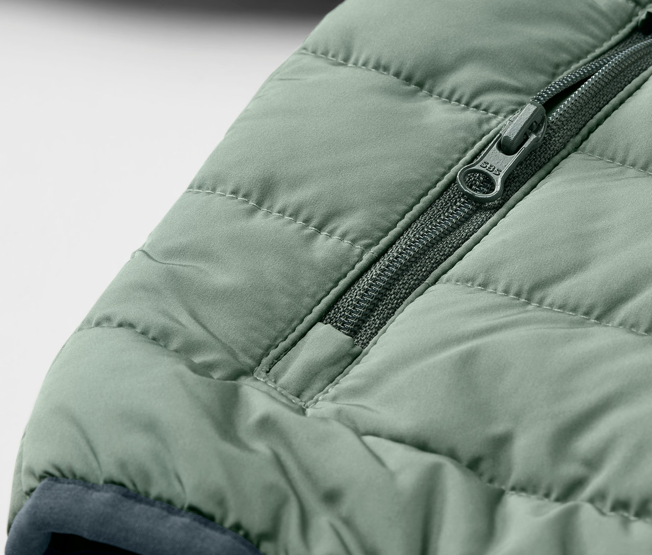 Détail d'un anorak matelassé vert pour enfants avec fermeture éclair.