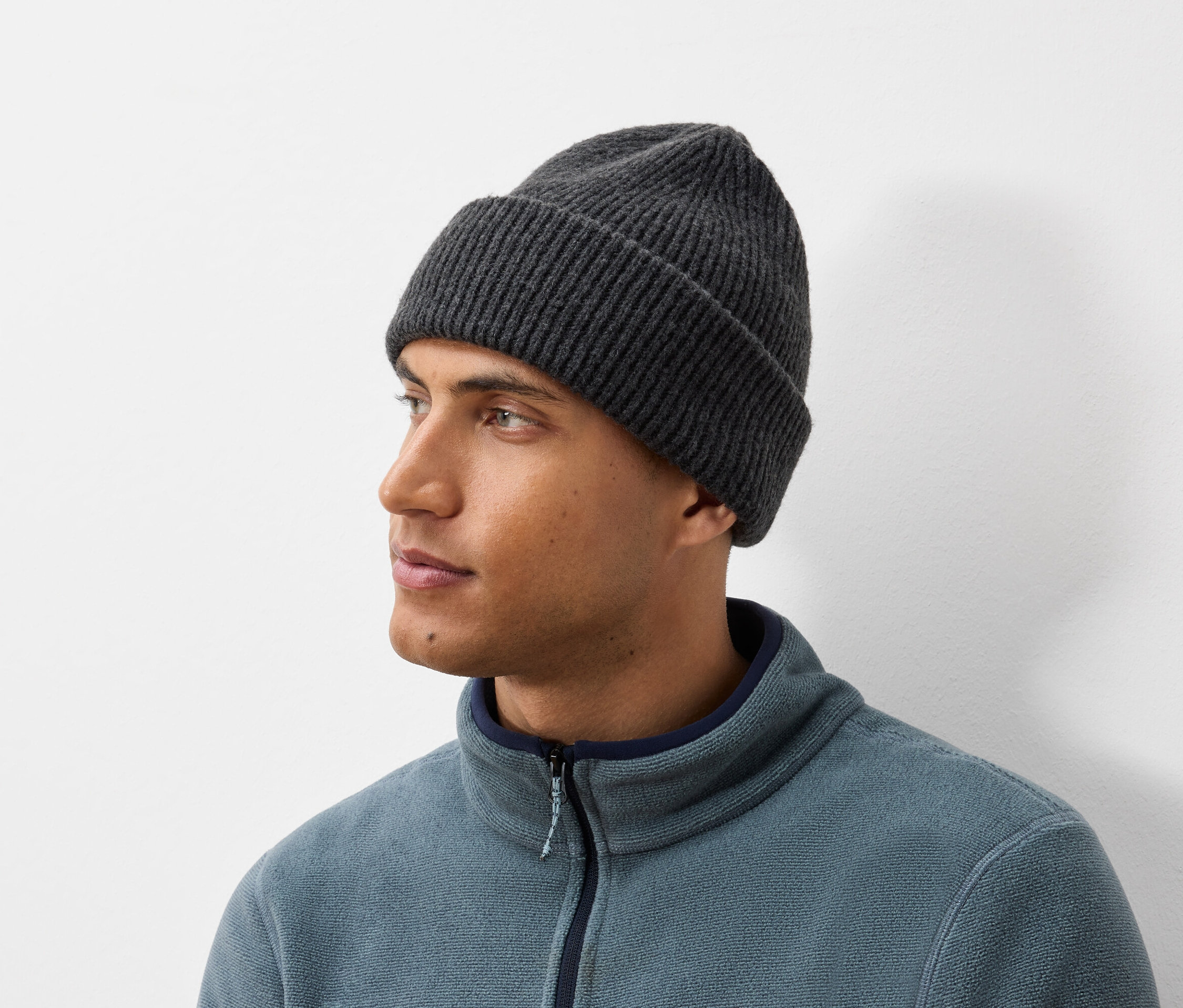 Portrait d'un homme portant un bonnet tricoté gris foncé et une veste en polaire bleu-gris.