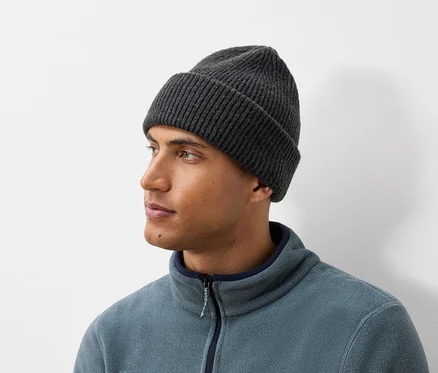 Portrait d'un homme portant un bonnet tricoté gris foncé et une veste en polaire bleu-gris.