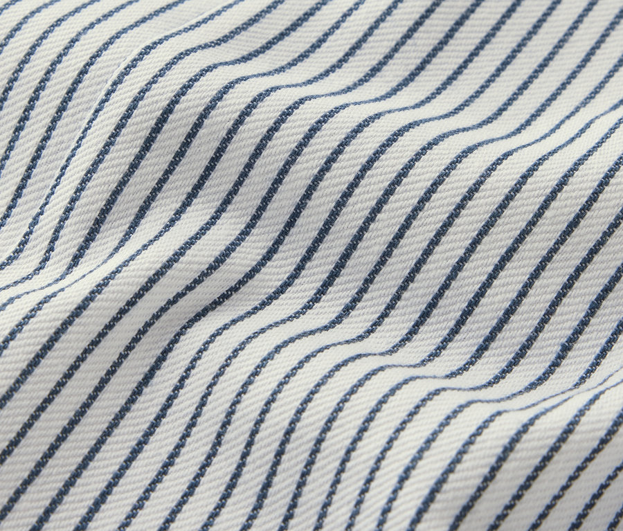 Gros plan sur une salopette tissée pour enfants avec des rayures bleues sur un fond blanc.