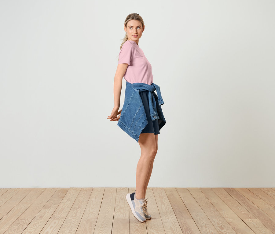 Femme posant en t-shirt basique rose, veste en jean et sweatshort bermuda.