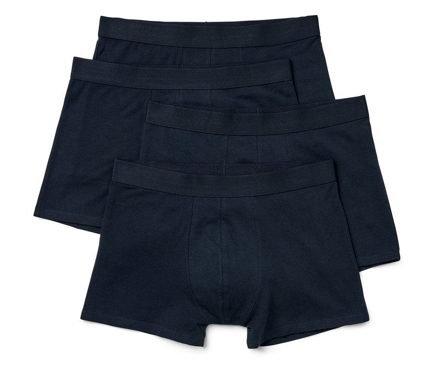 Quatre boxers noirs pour hommes sont posés les uns sur les autres.