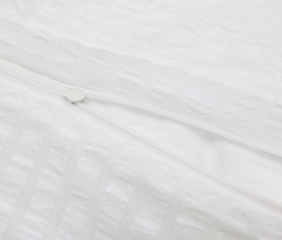 Détail d'une housse de couette blanche avec fermeture éclair.