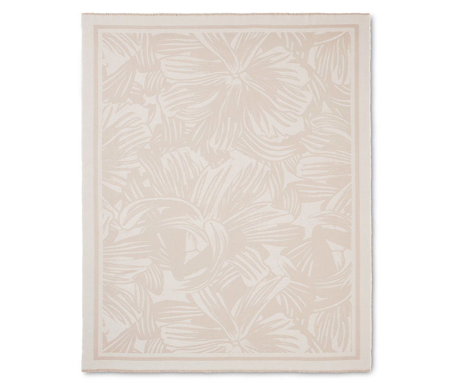 Couverture crème avec motif floral et bordure.