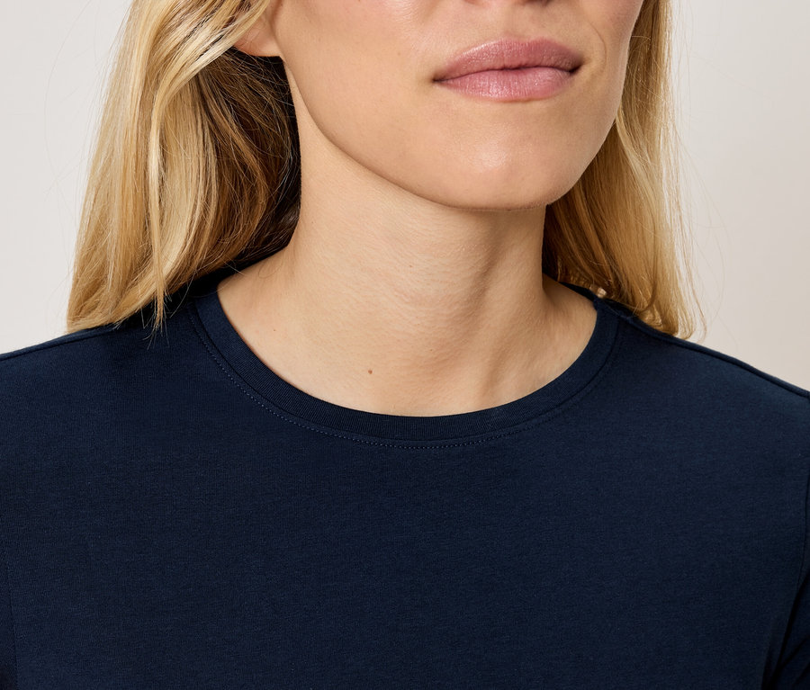 Haut du corps d'une femme blonde portant un t-shirt bleu marine.