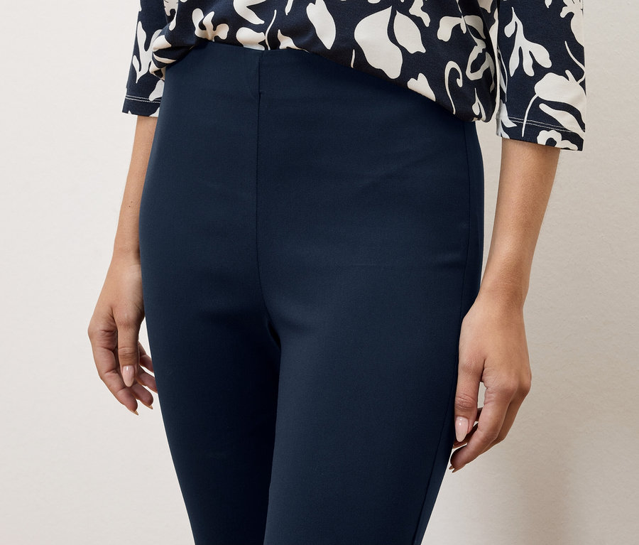 Gros plan d'une femme portant un pantalon bleu marine et un haut à fleurs.