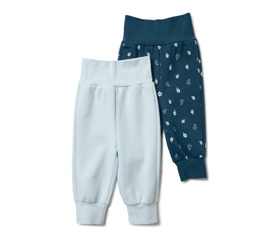 Deux pantalons de survêtement pour bébé : un bleu clair et un bleu foncé avec des petits voiliers blancs.