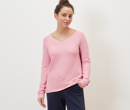 Femme posant dans un pull en maille rose.
