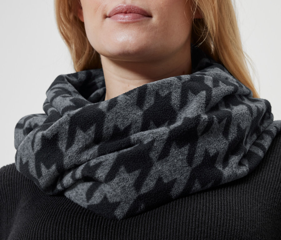 Gros plan d'une femme blonde portant un col gris à motif pied-de-poule et un pull noir.