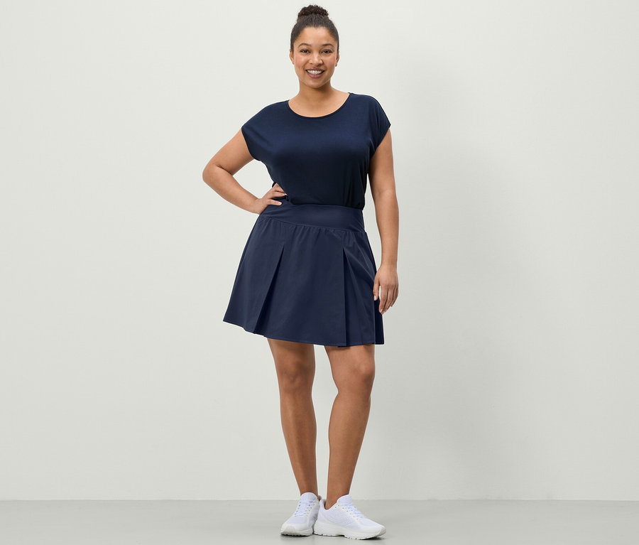 Femme posant dans une jupe de sport bleu foncé et un t-shirt de sport bleu.