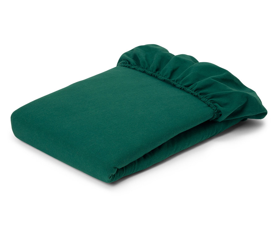 Drap-housse vert plié avec coins élastiques.